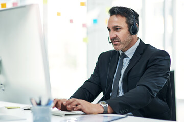 Fototapeta premium Call center, computer and man in workplace, headset and connection for help desk. Online consultation, corporate professional or person in office, typing or advice for tech support, contact us or crm