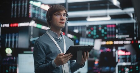 Fototapeta premium Successful Financial Analyst Surveying Real Time Trading Floor. Young Trader Stands in of High Tech Stock Exchange, Wearing Professional Headset and Corporate Lanyard. Concept of Top Tier Competence.