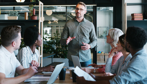 Business, team and man with discussion in meeting for editorial guidance, writing advice or feedback. Journalists, lead editor and talking in newsroom for topic delegation, story ideas and planning