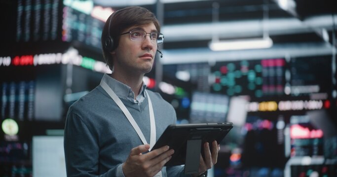 Investment Specialist Analyzing Stock Performance at Advanced Workstation, Standing on Live Trading Floor, Professional Interaction With Mobile Technology. Strategic Planning, Individual Leadership.