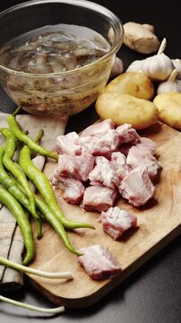 Raw meat and fresh green bell peppers on a wooden cutting board ready for cooking.
