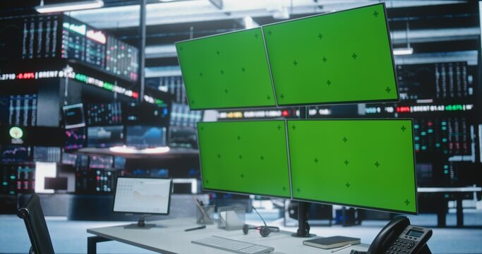 Empty Trading Desk With Green Screen Monitors in Modern Exchange Hub. Traders Workplaces With Multiple Displays Replaced Chroma Key Green Background, Positioned in Dynamic Investment Firm Environment.