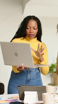 Vertical video: Raising laptop, woman in yellow top pointing to screen at meeting, outlining agenda