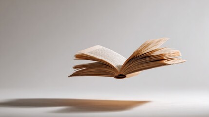 Fototapeta premium A vintage open book levitating with the shadows cast on the ground 
