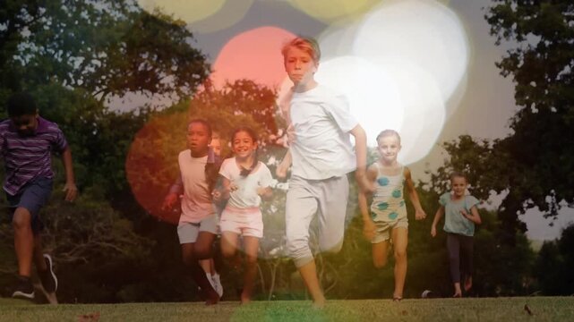 Running group of kids spreading toward lens across park, with bokeh overlay, wearing tees, shorts
