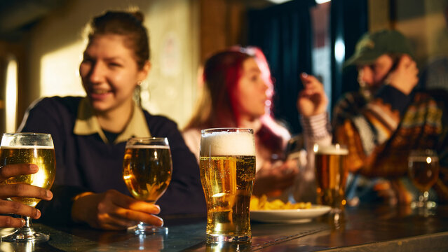 Beer glass on bar counter with friends socializing in background during relaxed pub evening for alcohol advertising, brewery promotion and hospitality marketing campaigns.
