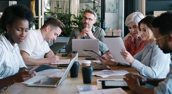 Business, team and man with laptop in meeting for editorial guidance, notes and brainstorming. Journalists, lead editor and tech with documents in newsroom for planning, writing advice and feedback