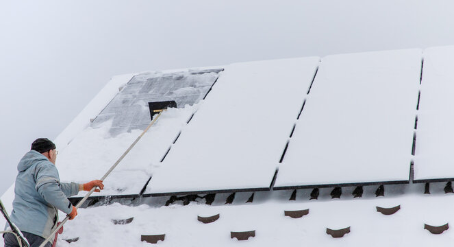 Clear snow from solar panels. Selective focus.
