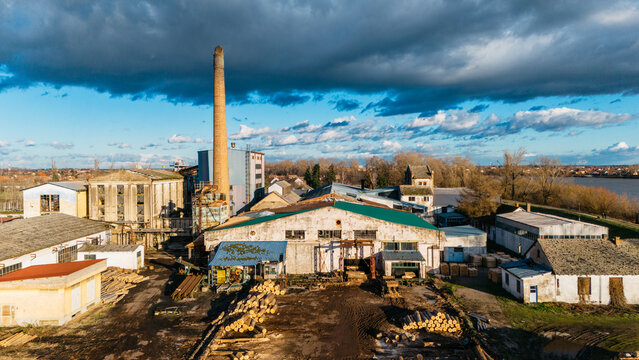 Aerial view of an industrial complex with a tall chimney casting shadows under a blue sky streaked with clouds, Sremska Mitrovica, Vojvodina, Serbia.