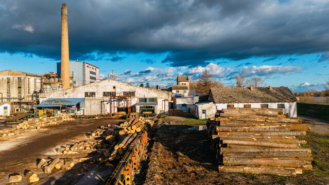 Aerial view of the industrial structures and stacks of logs under a sky streaked with drama, contrasting textures and tones, Sremska Mitrovica, Vojvodina, Serbia.