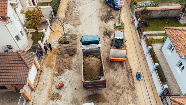 Aerial view of a construction site with a dump truck carrying soil, between houses with red tile roofs, Belgrade, City of Belgrade, Serbia.