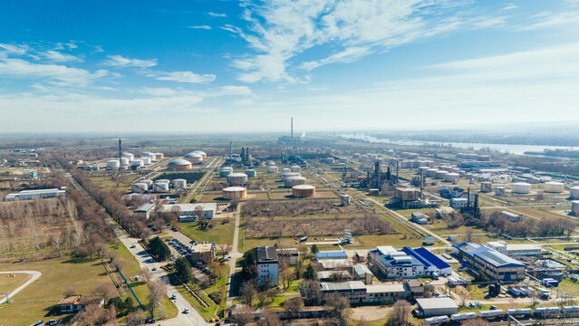 Aerial view of industrial zone with silver tanks and smokestacks puncturing the skyline under a bright blue sky, Novi Sad, Vojvodina, Serbia.