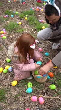 Father and daughter collecting colorful plastic easter eggs