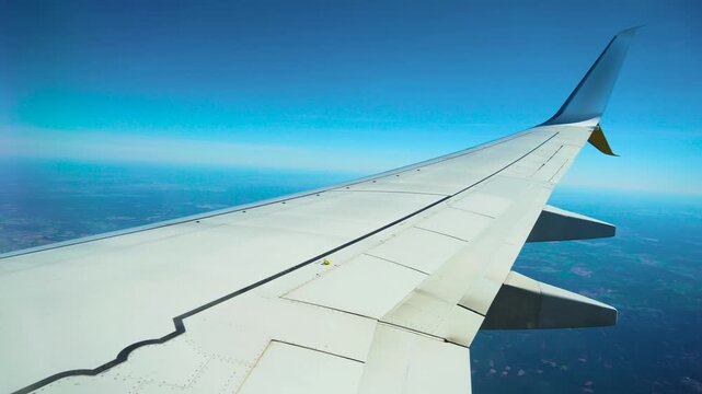 Aircraft flying above patchy forest and farmland. Passenger jet cruising over green and brown rural terrain. Commercial airplane gliding across mixed landscape of fields and woods