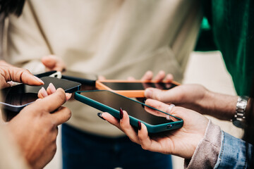 Close up view of teenagers hands using mobile phones outdoors. Social media and technology...