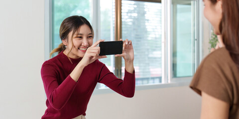 Fototapeta premium Capturing Smiles. Woman taking photo of her friend with smartphone.