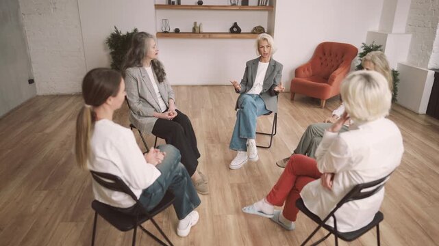 Group therapy for divorced senior women, ladies sitting in circle and talking. Pretty female persons meeting in office of psychologist for talking about life, relationship and health, women community