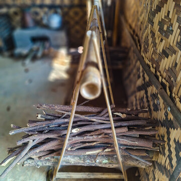 Stacked firewood hanging on a wooden rack inside a traditional bamboo kitchen. This natural fuel storage method reflects sustainable rural cooking practices and traditional village life.