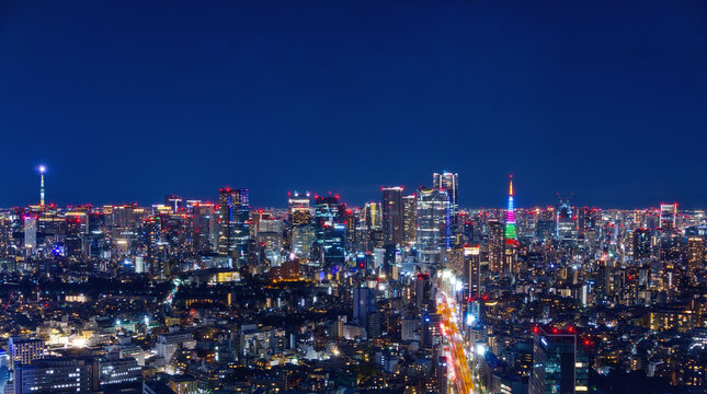 Vibrant night view of Tokyo city skyline at twilight. Illuminated skyscrapers and iconic urban landmarks under dark blue sky, representing Japan's metropolitan nightlife and capital city. Tokyo tower.