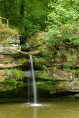 Waterfall cascading into pond among mossy rocks in Stvolinky