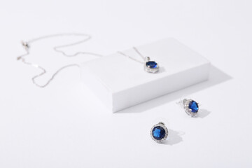 Elegant silver necklace and earrings with blue gemstones on white background