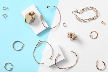 Stylish golden rings, bracelets and earring with plaster podiums on color background