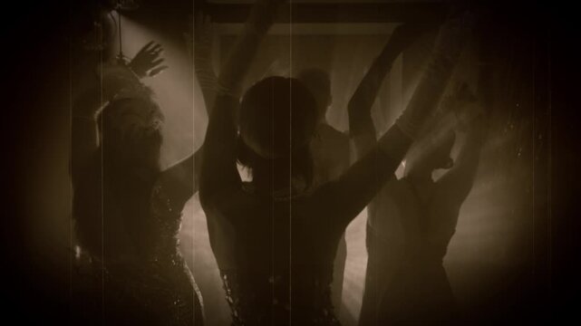 1920s old style sepia color film, people hang out dancing crowd hands arms raised up waving to sides in dark night club. Youth flapper female male have fun at dance floor roaring twenties retro party.