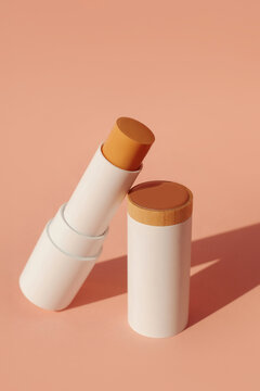 Minimal open cream foundation stick for contouring, bronzer stick, corrector make up with wooden cap on pastel beige peach background. Modern packaging tube mock up, decorative cosmetic concept