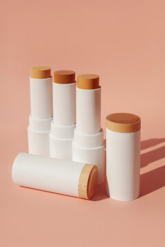 Shade range, lineup, color collection of cream foundation sticks for contouring, bronzer stick, corrector make up on pastel beige peach background. Packaging tube mock up, decorative cosmetic concept
