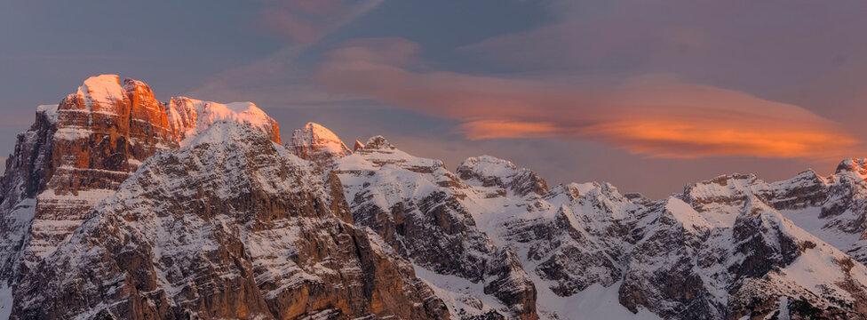Snow-covered Brenta mountain peaks glow with the warm light of the setting sun, set against a soft, colorful sky. Adamello Brenta Natural Park,Madonna di Campiglio,Trentino,Italy