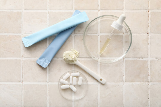 Collagen jelly sticks, pills, pipette and teaspoon of powder on beige tile background