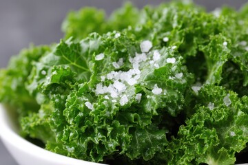 Obraz premium Fresh green kale with coarse salt displayed in a bowl on a dark background, highlighting its natural texture and freshness for healthy cooking ideas.