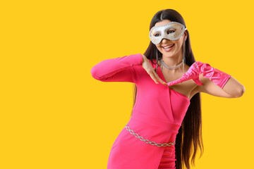Beautiful woman in carnival mask on yellow background