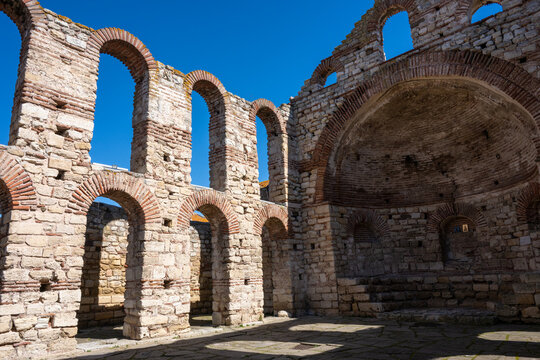 the Church of Saint Sophia ruins in Nesebar, Bulgaria, showcasing the rhythmic Byzantine arches and the central apse under a clear blue sky.
