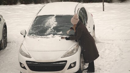 Odśnieżanie zasypanego śniegiem samochodu w okresie zimowym © tomo81