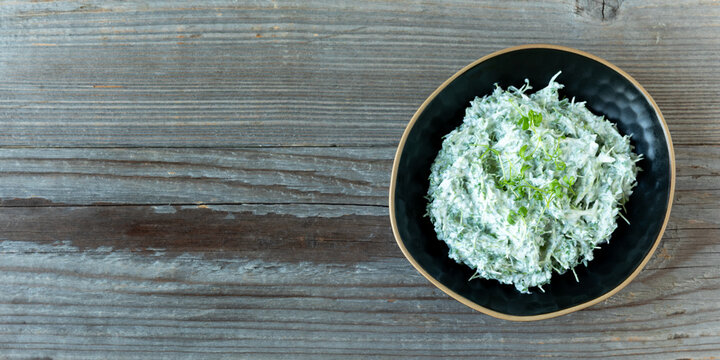 Homemade curly cress microgreens and yogurt dip in a bowl. Rustic wooden background with free copy space. 
