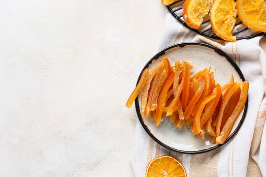 Tasty candied orange peels and slices on light background