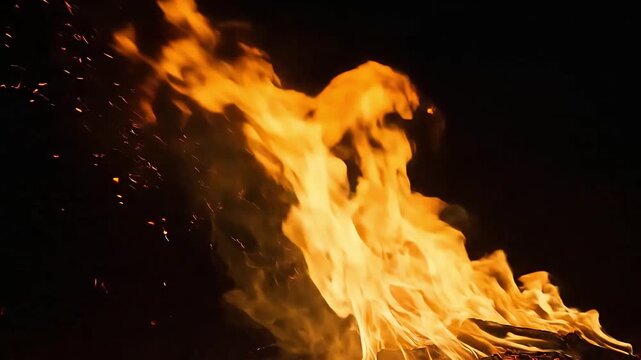 Flames rise high in dark with sparks flying around fiery scene