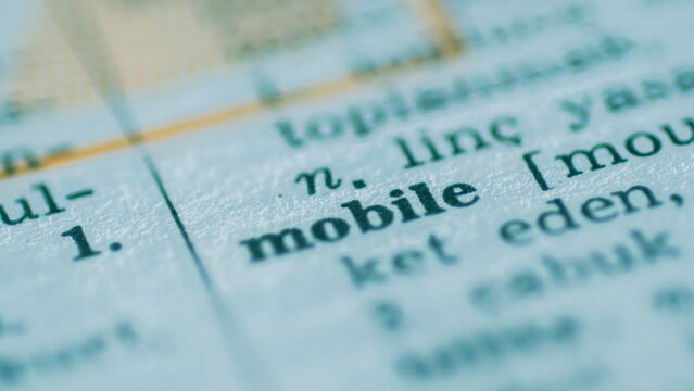 Extreme close-up macro shot of the word "mobile" in a dictionary. Concept for telecommunications, digital technology, mobility, and modern communication.