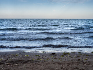 Fototapeta premium Waves rolling on sandy Black Sea beach at sunset in Saturn resort, Romania