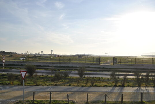 Airplane landing over runway at sunset with road in foreground