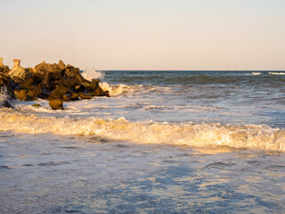 Golden sunlight waves breaking near rocky Black Sea shore © Dan Badiu