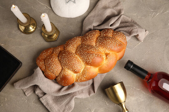 Traditional challah bread with wine and candles on grey grunge table. Shabbat Shalom