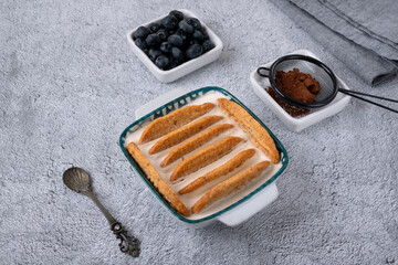 Trendy Japanese yogurt cheesecake with cookies biscuit on a gray background. Blueberries and cocoa...