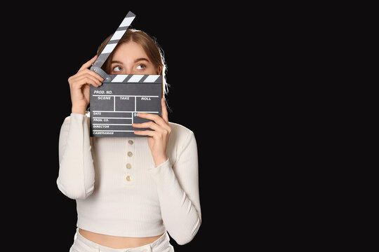 Young actress with movie clapper on black background