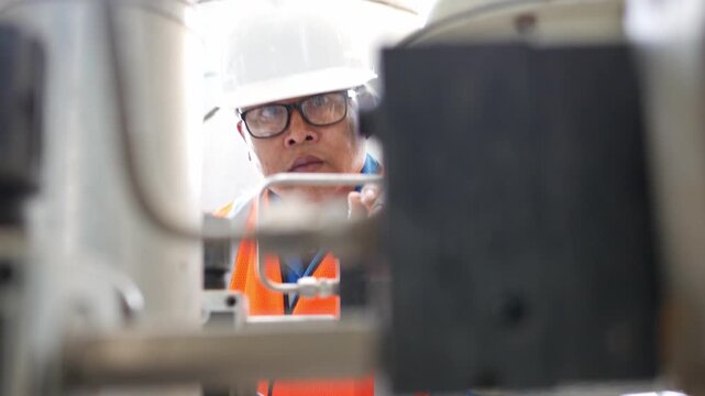 Experienced engineer inspecting refinery equipment in a chemical and petroleum plant process area, ensuring system readiness and operational efficiency in large scale industrial production.