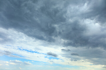 Obraz premium Dramatic dark storm clouds over blue sky background with approaching bad weather and moody atmosphere