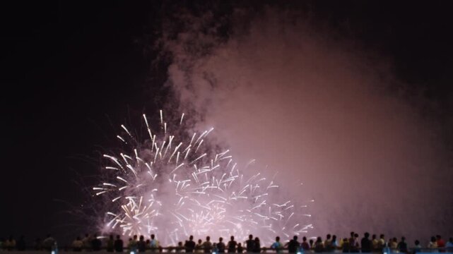 Beautiful Fireworks Display Over the City at Night with People Watching.