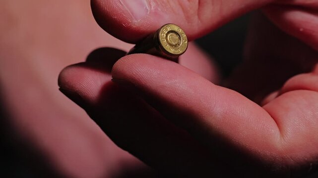 Man slowly rolling live ammunition cartridge between fingers as deterrence