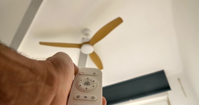 Ceiling Fan Remote Control: A person's hand reaches to control a sleek ceiling fan, representing technological innovation and home comfort. 
